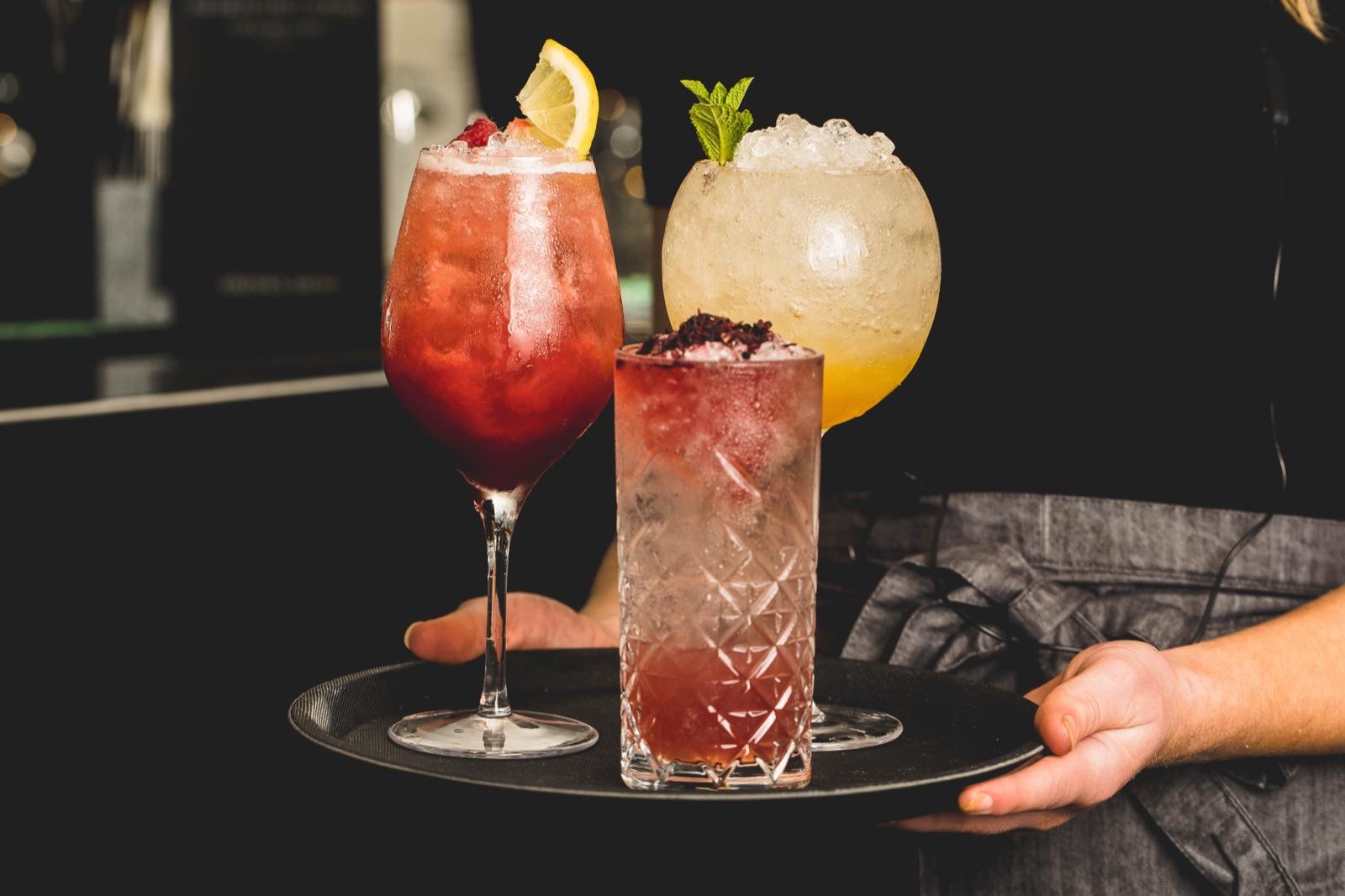 A server holding a tray of cocktails